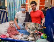 25 December 2023; Eight month old Holly Browne, her father, Vincent, from Carrigrohane, Cork, and Dublin footballer Brian Howard with the Sam Maguire Cup during the All-Ireland Senior Football Championship winners visit to Children's Health Ireland at Temple Street in Dublin. Photo by Ray McManus/Sportsfile