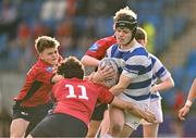 25 January 2024; James McDonald of Good Counsel, New Ross, is tackled by Lachlan Honan, left, and Mark Murray, 11, of CUS during the Bank of Ireland Leinster Rugby Schools Father Godfrey Cup semi-final match between Good Counsel, New Ross and CUS at Energia Park in Dublin. Photo by Ben McShane/Sportsfile