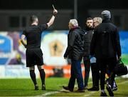 16 February 2024; Referee Eoghan O'Shea shows a yellow card to Galway United assistant manager Ollie Horgan, right, during the SSE Airtricity Men's Premier Division match between Galway United and St Patrick's Athletic at Eamonn Deacy Park in Galway. Photo by Seb Daly/Sportsfile