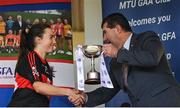 9 March 2024; UCC captain Mairead Bennett is presented with the cup by Uachtarán Cumann Peil Gael na mBan, Mícheál Naughton after the 2024 Ladies HEC Lynch Cup final match between Munster Technological University Cork and University College Cork at MTU Cork. Photo by Brendan Moran/Sportsfile