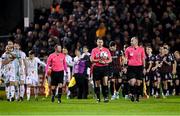 8 March 2024; Match officials, from left, assistant referee Brian Fenlon, referee Paul McLaughlin and assistant referee Eoin Harte lead the side's out for the SSE Airtricity Men's Premier Division match between Bohemians and Shelbourne at Dalymount Park in Dublin. Photo by Stephen McCarthy/Sportsfile