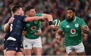 16 March 2024; Calvin Nash of Ireland offloads to team-mate Bundee Aki, right, as he is tackled by Huw Jones and Kyle Steyn of Scotland, hidden, during the Guinness Six Nations Rugby Championship match between Ireland and Scotland at the Aviva Stadium in Dublin. Photo by Brendan Moran/Sportsfile