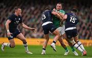 16 March 2024; James Lowe of Ireland is tackled by Huw Jones, 13, and Blair Kinghorn of Scotland during the Guinness Six Nations Rugby Championship match between Ireland and Scotland at the Aviva Stadium in Dublin. Photo by Brendan Moran/Sportsfile
