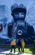 20 April 2024; Donegal supporters pass the Boy in Gas Mask mural on their way to Celtic Park for the Ulster GAA Football Senior Championship quarter-final match between Derry and Donegal at Celtic Park in Derry. Photo by Stephen McCarthy/Sportsfile