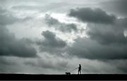 14 May 2024; A member of the public walks their dog amid dark clouds during Munster rugby squad training at University of Limerick in Limerick. Photo by Brendan Moran/Sportsfile