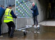 20 May 2024; The Dublin bus driver Eugene Riordan is helped across a puddle using the man of the match board before the Electric Ireland Leinster GAA Football Minor Championship Final match between Longford and Dublin at Glenisk O'Connor Park in Tullamore, Offaly. Photo by David Fitzgerald/Sportsfile