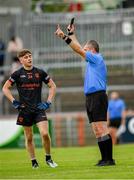 26 May 2024; Referee Barry McMenamin hands out a black card to Ross Marsden from Armagh during the Electric Ireland Ulster GAA Football Minor Championship final match between Armagh and Derry at O'Neill's Healy Park in Omagh, Tyrone. Photo by Philip Fitzpatrick/Sportsfile