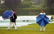 8 August 2004; Ireland's Andrew White attempts to repair his umberella as team-mate Eoin Morgan, left, and Groundsman Carl McDermott consider the playing conditions. ICC Inter Continental Cup, European Group Match, Ireland v Scotland, Clontarf Cricket Club, Clontarf, Dublin. Picture credit; Brian Lawless / SPORTSFILE