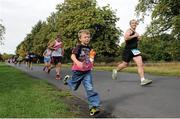 21 September 2013; Andre Tully, from Dublin, in jovial mood as a young child runs alongside the track during the final stages of the half-marathon Airtricity Dublin race series. Phoenix Park, Dublin. Picture credit: Pat Murphy / SPORTSFILE