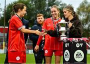 13 October 2024; Republic of Ireland international Jamie Finn presents the cup to Keva Deegan of Shelbourne, left, and Madeleine McKinley of Shelbourne after the EA SPORTS WU19 Cup match between Shelbourne and Athlone Town at Tolka Park in Dublin. Photo by Tyler Miller/Sportsfile