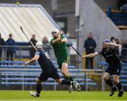 26 October 2024; Aidan McCarthy of Ireland in action against Scotland players, from left, Finlay MacRae and Robert Mabon during the Shinty International match between Ireland and Scotland at Cusack Park in Ennis, Clare. Photo by John Sheridan/Sportsfile