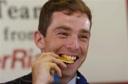 30 August 2004; Olympic gold medalist Cian O'Connor bites on his medal during a press conference on the arrival home of the Irish Olympic team from Athens. Dublin Airport, Dublin. Picture credit; Pat Murphy / SPORTSFILE