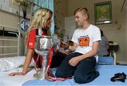 30 September 2013; Cork's Brid Stack with Derek McDonnell, from Cabra, Dublin, and the Brendan Martin cup on a visit by the All-Ireland Ladies Football Champions to Temple Street Children's University Hospital, Temple Street, Dublin.  Picture credit: Brendan Moran / SPORTSFILE