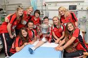 30 September 2013; Cork players, clockwise from top left, Roisin Phelan, Angela Walsh, Jess O'Shea, Vera Foley, Sarah Harrington, Nollaig Cleary, Annie Walsh and Orlagh Farmer with Tyler Cumberton, age 14, from Hardwicke Stret, Dublin, and the Brendan Martin cup on a visit by the All-Ireland Ladies Football Champions to Temple Street Children's University Hospital, Temple Street, Dublin.  Picture credit: Brendan Moran / SPORTSFILE