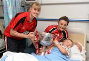 30 September 2013; Cork's Emma Farmer and Annie Walsh with Mark Grace, age 7, from Toomevara, Co. Tipperary, and the Brendan Martin cup on a visit by the All-Ireland Ladies Football Champions to Temple Street Children's University Hospital, Temple Street, Dublin.  Picture credit: Brendan Moran / SPORTSFILE
