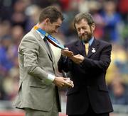 12 September 2004; President of the GAA Sean Kelly, admires the Gold Medal won by Irish Olympic Gold Medallist Cian O'Connor in Athens recently, after making a special presentation to him at half-time. Guinness All-Ireland Senior Hurling Championship Final, Cork v Kilkenny, Croke Park, Dublin. Picture credit; Brendan Moran / SPORTSFILE *** Local Caption *** Any photograph taken by SPORTSFILE during, or in connection with, the 2004 Guinness All-Ireland Hurling Final which displays GAA logos or contains an image or part of an image of any GAA intellectual property, or, which contains images of a GAA player/players in their playing uniforms, may only be used for editorial and non-advertising purposes.  Use of photographs for advertising, as posters or for purchase separately is strictly prohibited unless prior written approval has been obtained from the Gaelic Athletic Association.