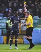 18 April 2025; Referee Damien MacGraith shows Mipo Odubeko of Shelbourne a yellow card during the SSE Airtricity Men's Premier Division match between Drogheda United and Shelbourne at Sullivan & Lambe Park in Drogheda, Louth. Photo by Ben McShane/Sportsfile