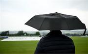 12 June 2025; A spectator waits under an umbrella before match one of the T20 International Series between Ireland and the West Indies at Bready Cricket Club in Magheramason, Tyrone. Photo by Seb Daly/Sportsfile