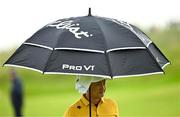 17 July 2025; Haotong Li of China shelters from the rain during day one of The 153rd Open Championship at Royal Portrush Golf Club in Portrush, Antrim. Photo by Ramsey Cardy/Sportsfile