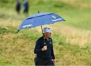 17 July 2025; Lee Westwood of England shelters from the rain with an umbrella during day one of The 153rd Open Championship at Royal Portrush Golf Club in Portrush, Antrim. Photo by Ramsey Cardy/Sportsfile