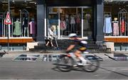 24 July 2025; A cyclist rides past a shopkeeper before competing in the girls road race during day four of the 2025 European Youth Summer Olympic Festival in Kumanovo, North Macedonia. Photo by Tyler Miller/Sportsfile