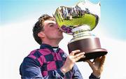 31 July 2025; Jockey Jack Kennedy celebrates by kissing the trophy after winning the Guinness Galway Hurdle Handicap on Ndaawi during day four of the Galway Races Summer Festival at Ballybrit Racecourse in Galway. Photo by Seb Daly/Sportsfile