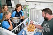 4 August 2025; TG4 All-Ireland Ladies Senior Football Champions and Dublin footballers Aoife Curran, Rebecca McDonnell and Laura Grendon pictured with the Brendan Martin Cup and Billie Madden, aged 4 weeks, and his father Willie, during a visit by the players to Children's Health Ireland at Crumlin, Dublin. Photo by Sam Barnes/Sportsfile
