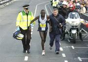 25 October 2004; Paul Kanda, of Kenya, is helped the last few meters by medical personnel and a race official. adidas Dublin City Marathon 2004. Merrion Square, Dublin. Picture credit; Brendan Moran / SPORTSFILE
