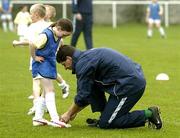 29 March 2005; Former Republic of Ireland international Niall Quinn helps to tie up the lace of Clare McGarry's boots during the Dublin Docklands Festival of football. This event, which takes place from 29th to 31st March, has been developed to help young people from the Docklands area of Dublin to develop their skills and come more confident and accomplished players. Teaching the soccer skills are soccer stars Niall Quinn, Ray Houghton, Don Givens, Bobby Saxton and Chris Nichol. Tolka Rovers FC, Frank Cooke Park, Griffith Avenue, Dublin. Picture credit; Brendan Moran / SPORTSFILE