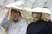 8 May 2006; Martin and Joan Hunt take shelter underneath an umpires coat. Corn Aghais, St Malachy's Edenmore v Gaelscoil Taobh na Coille, Allianz Cumann na mBunscoil Finals, Croke Park, Dublin. Picture credit: Damien Eagers / SPORTSFILE
