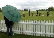 16 May 2006; A golf fan shelters from a shower as he watches golfers practice on the driving range. Nissan Irish Open Practice, Carton House Golf Club, Maynooth, Co. Kildare. Picture credit; Brian Lawless / SPORTSFILE