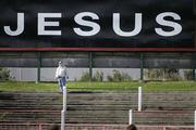 19 August 2006; A Newry Fan stops to watch the match under the Jesus sign. CIS Insurance Cup, Glentoran v Newry City, The Oval, Belfast, Co. Antrim. Picture credit: Russell Pritchard / SPORTSFILE