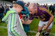 12 August 2014; Former Kilkenny hurler DJ Carey signs an autograph for Daithí Dowling, aged 7, from Allen, Co. Kildare, after the game. Ireland’s GAA and Horse Racing ‘All Stars’ got their hurleys out for cancer research on Tuesday night at Saint Conleth’s Park, Newbridge, Kildare for a celebrity hurling match in aid of the Irish Cancer Society to raise money for cancer research. The event, which was organised by horseracing legend Jim Bolger, along with champion jockey Davy Russell, saw a host of Irish hurling and horse racing stars come together for a fantastic game, which also boasted celebrity referees, lineswomen and umpires - who included DJ Carey, Katie and Ted Walsh, and Cyril Farrell - to name but a few. Irish Cancer Society's Hurling for Cancer Research 2014, Jim Bolger's Stars v Davy Russell's Best, St. Conleth’s Park, Newbridge, Co. Kildare. Irish Cancer Society's Hurling for Cancer Research 2014, Jim Bolger's Stars v Davy Russell's Best, St. Conleth’s Park, Newbridge, Co. Kildare. Picture credit: Barry Cregg / SPORTSFILE