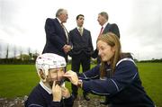 27 October 2006; The National Standards Authority (NSAI) launched a new standard, I.S. 355, of helmets for hurlers and camogie players at Erin's Own GAA Club, Cork. Requirements will have to be met at all levels concerning construction of the helmet including shock absorption, sliothar and hurley impact. All hurlers under the age of 21 and all camogie players under the age og 18 are required to wear a helmet when playing. Pictured at the launch is Aoife O'Connor, age 8, from the Erin's Own Club getting some assistance from Cork camogie captain Joanne O'Callaghan, with back, from left, Dan Tierney, Chairman, NSAI, Cork hurler Ronan Curran and Michael Ahern, TD, Minister for Trade and Commerce. Erin's Own GAA Club, Pairc Ui Chonaill, Cork. Picture credit: Brendan Moran / SPORTSFILE