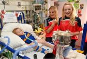 29 September 2014; Cork players Mairead Corkery, left, and Vera Foley with two year old Billy Goulding from Birr, Co. Offaly and the Brendan Martin Cup during a visit to Temple Street Childrens Hospital, Dublin. Photo by Sportsfile