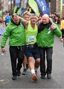27 October 2014; Patrick O'Donoghue, Tipperary, is assisted as he makes his way down the finishing straight on his way to finishing the SSE Airtricity Dublin Marathon 2014. Picture credit: Ray McManus / SPORTSFILE
