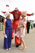 1 May 2015; Laura Ivory, Tipperary, left, and Grace Ormond, Tipperary are greeted by stilt walker Vijaya Bateman from Artastic. Punchestown Racecourse, Punchestown, Co. Kildare. Picture credit: Cody Glenn / SPORTSFILE