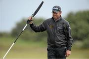 27 May 2015; Lee Westwood holding the flag at the 9th green waiting for the rain to subside. Dubai Duty Free Irish Open Golf Championship 2015, Pro-Am. Royal County Down Golf Club, Co. Down. Picture credit: Oliver McVeigh / SPORTSFILE
