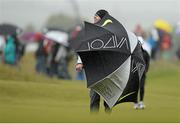 27 May 2015; Rory McIlroy taking shelter from the elements on the 18th fairway. Dubai Duty Free Irish Open Golf Championship 2015, Pro-Am. Royal County Down Golf Club, Co. Down. Picture credit: Oliver McVeigh / SPORTSFILE