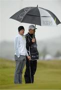 27 May 2015; Rory McIlroy and caddie JP Fitzgerald, taking shelter from the elements on the 18th fairway. Dubai Duty Free Irish Open Golf Championship 2015, Pro-Am. Royal County Down Golf Club, Co. Down. Picture credit: Oliver McVeigh / SPORTSFILE