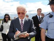 29 July 2008; Republic of Ireland manager Giovanni Trapattoni signs an autograph under the watchful eye of a member of An Garda Síochána on his arrival at the second day of the Galway Racing Festival. Galway Racing Festival - Tuesday, Ballybrit, Galway. Picture credit: Stephen McCarthy / SPORTSFILE