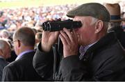 30 July 2015; A racegoer keeps an eye on the horses in the parade ring from the grandstand with binoculars. Galway Racing Festival, Ballybrit, Galway. Picture credit: Cody Glenn / SPORTSFILE
