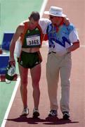 29 September 2000; Jamie Costin of Ireland is helped from the track by an official following the men's 50km walking race during day 15 of the 2000 Sydney Olympics in Sydney, Australia. Photo by Brendan Moran/Sportsfile