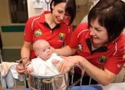 28 September 2009; Jack Mulvihill, from Dublin, sitting in the Brendan Martin Cup with players and sisters Norita Kelly, left, and Mairead Kelly during a visit by the winning All-Ireland Cork Ladies Football team to Our Lady's Hospital for Sick Chidren in Crumlin. Crumlin, Co. Dublin. Photo by Sportsfile