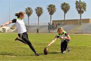 17 March 2016; TG4 LGFA All Star Caroline O'Hanlon, Armagh, kicks an American Football with the help of team-mate Sinead Kernan during a demonstration of Ladies Football to students from Mar Vista High School. TG4 Ladies Football All-Star Tour, Mar Vista High School, Imperial Beach. California, USA. Picture credit: Brendan Moran / SPORTSFILE