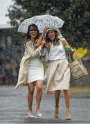 6 April 2016; Michelle Courtney, left, from Mullingar, Co. Westmeath, and Jane Boland, from Portmarnock, Co. Dublin, make their way in to the racecourse during a heavy shower. Leopardstown, Co. Dublin. Photo by Sportsfile