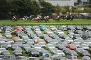 29 July 2010; The runners and riders in the Perfect Pint Beginners Steeplechase race past a packed car park. Galway Racing Festival 2010, Ballybrit, Galway. Picture credit: Ray McManus / SPORTSFILE