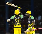 4 July 2016; Chris Gayle, left, of Jamaica Tallawahs celebrates his century by throwing his bat in the air as team-mate Andre Russell looks on during Match 7 of the Hero Caribbean Premier League between Trinbago Knight Riders and Jamaica Tallawahs at Queen's Park Oval, in Port of Spain, Trinidad. Photo by Randy Brooks/Sportsfile