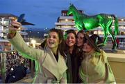 16 March 2017; Harper Adams University students, from left, Jane Shaw, Rosie Bryce, Rosie Cowie, and Lauren Miller take a selfie in front of a statue of 1966 Gold Cup-winner Arkle, trained by Tom Dreaper Mullins and ridden by Pat Taaffe, which is illuminated green for St. Patrick's Day during the Cheltenham Racing Festival at Prestbury Park in Cheltenham, England. Photo by Cody Glenn/Sportsfile