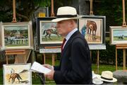 28 May 2017; A racegoer walks past the art of John Fitzgerald during the Tattersalls Irish Guineas Festival at The Curragh, Co Kildare. Photo by Cody Glenn/Sportsfile